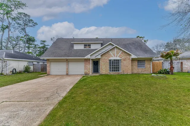 a view of a yard in front of a house with plants and large tree