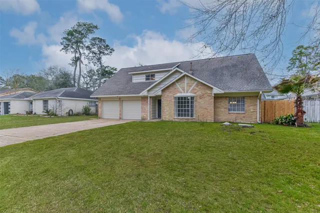 a view of a house with a big yard plants and large tree