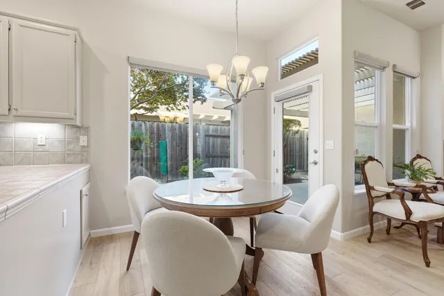 a dining room with wooden floor a chandelier a wooden table and chairs