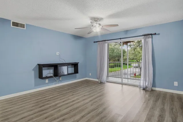 a view of a livingroom with wooden floor fan and a window