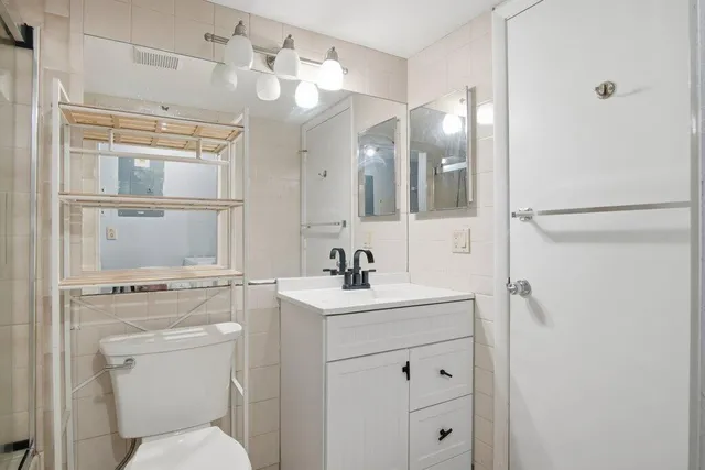 a bathroom with a sink a toilet a mirror and shower