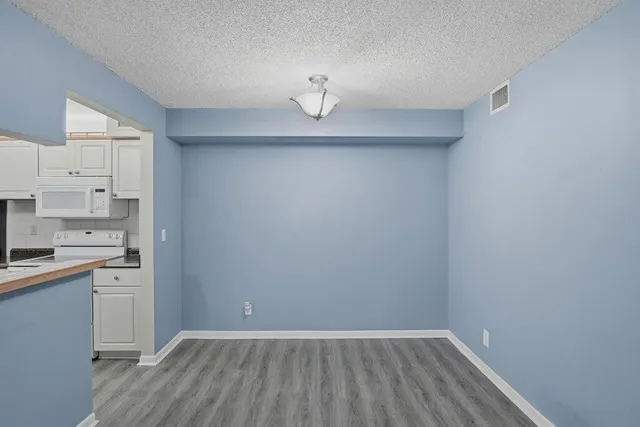 a view of a kitchen with white cabinets and wooden floor