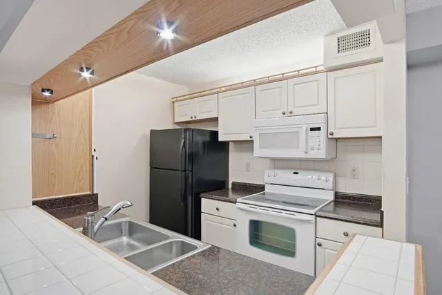 a kitchen with a refrigerator sink and cabinets