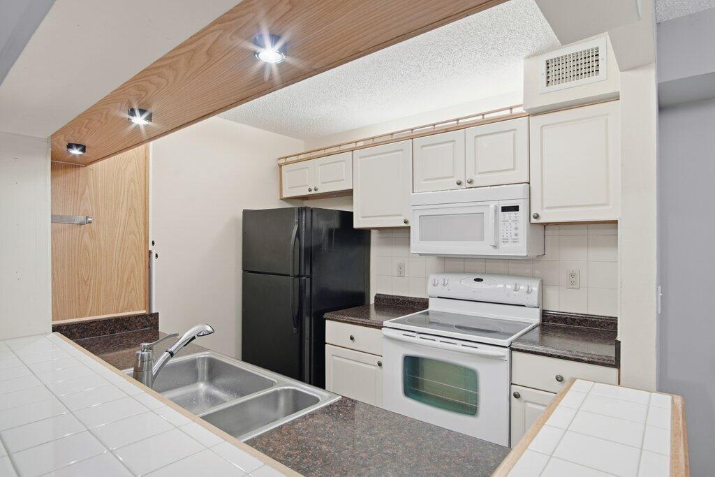 2500 Southeast Anchorage Cove, Unit B2 Port St. Lucie, FL 34952 - Photo 9 of 25 a kitchen with a refrigerator sink and cabinets