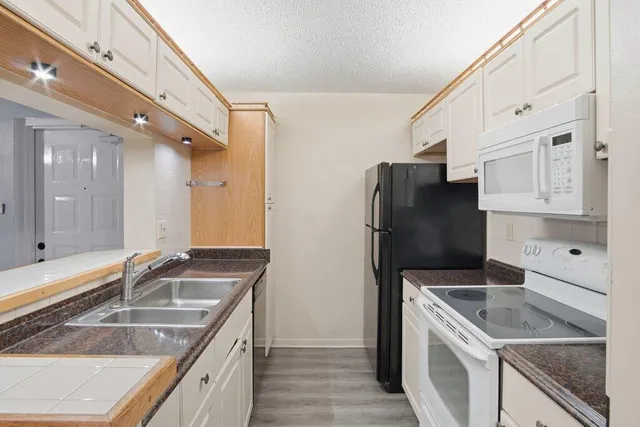 a kitchen that has a sink a stove and a refrigerator