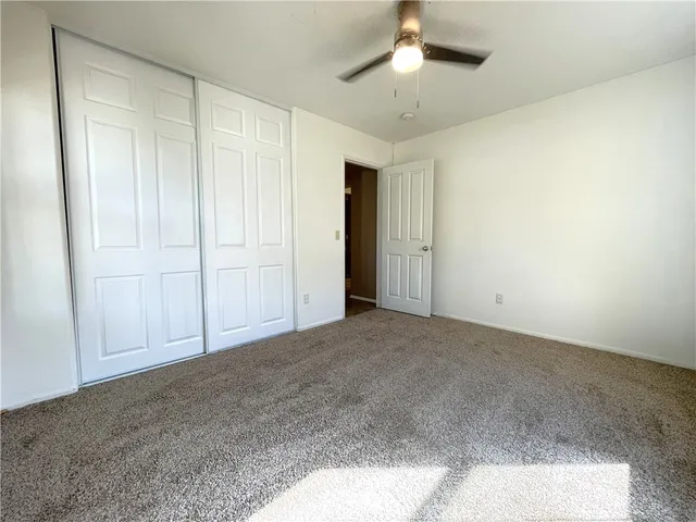 a view of an empty room and chandelier fan