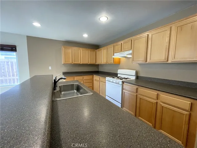 a kitchen with granite countertop a sink dishwasher stove and cabinets