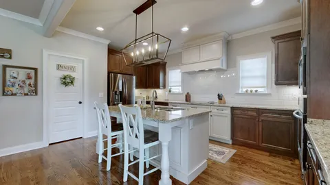 a kitchen with stainless steel appliances kitchen island granite countertop a wooden floor and white cabinets
