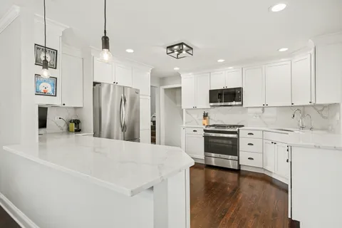 a kitchen with granite countertop a refrigerator stove and sink