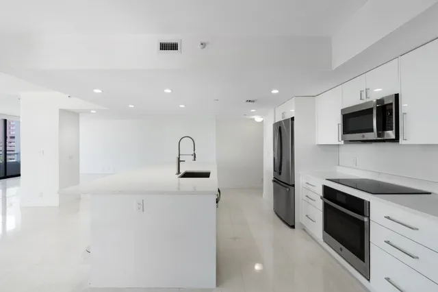 a large kitchen with stainless steel appliances kitchen island a large counter top space and cabinets