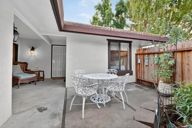 a patio with a table and chairs and potted plants