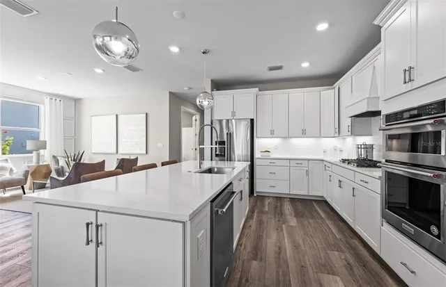 a kitchen with stainless steel appliances sink stove refrigerator and cabinets