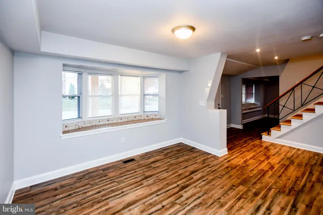 a kitchen with stainless steel appliances granite countertop a refrigerator a sink dishwasher a stove and white countertops with wooden floor