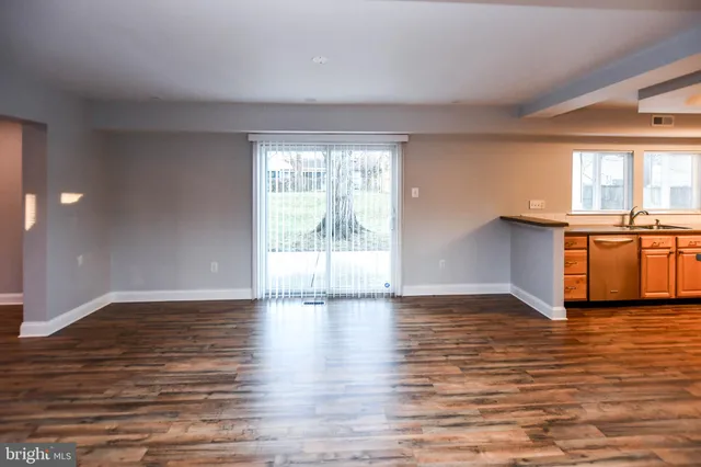 a kitchen with stainless steel appliances granite countertop a refrigerator a sink dishwasher a stove and white countertops with wooden floor