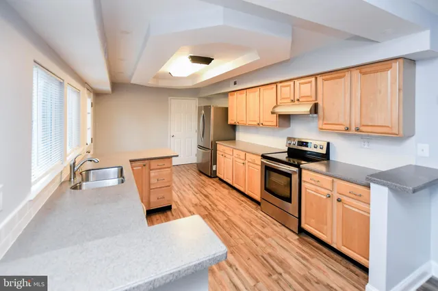 a kitchen with stainless steel appliances granite countertop a sink a stove and a wooden floors