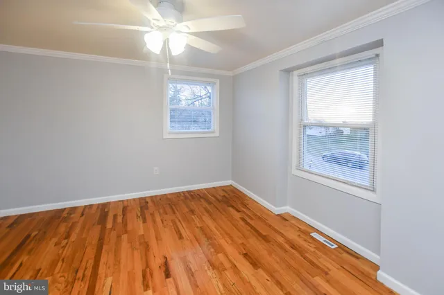 a view of empty room with wooden floor and fan
