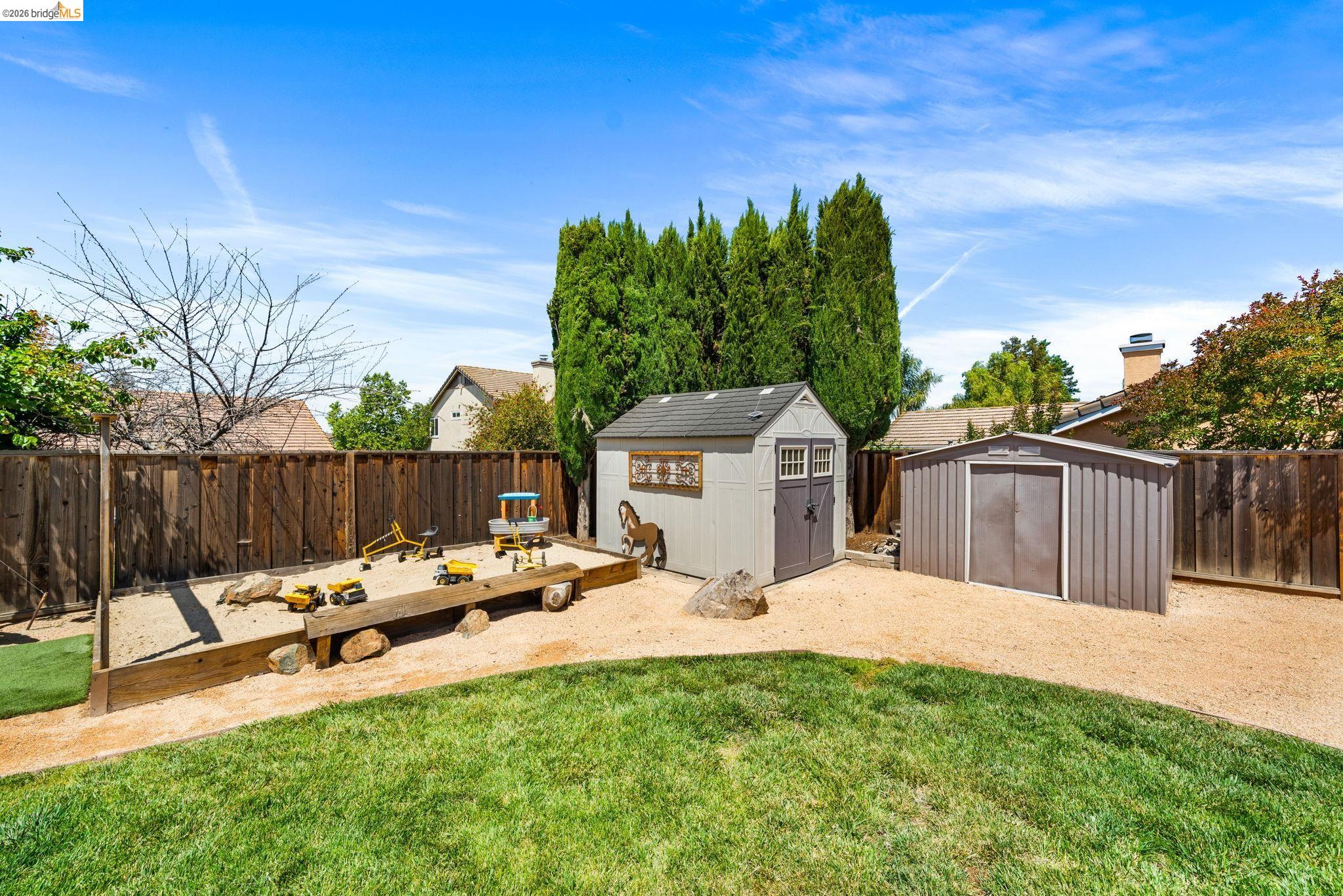 1186 El Rio Court Livermore, CA 94551 - Photo 45 of 60 Expansive backyard featuring a manicured lawn, a large sand area with wood borders, and two storage sheds