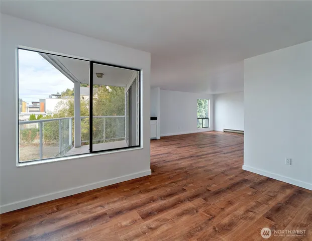 a view of an empty room with wooden floor and a window