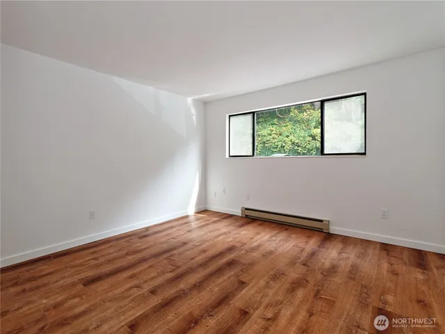 a view of an empty room with wooden floor and a window