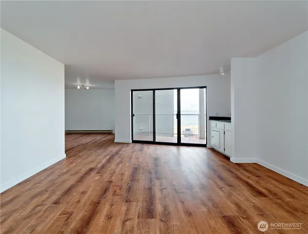a view of an empty room with wooden floor and a window