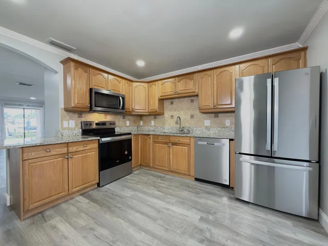 a kitchen with stainless steel appliances granite countertop a refrigerator stove microwave and sink