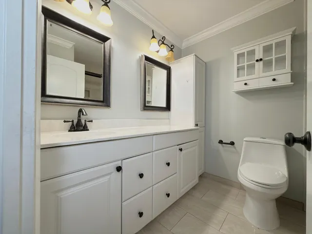 a bathroom with a toilet sink double vanity and mirror