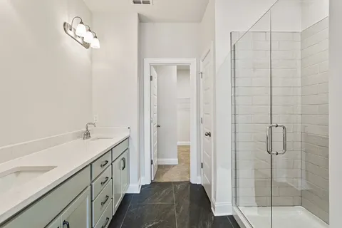 a bathroom with a double vanity sink a toilet and shower
