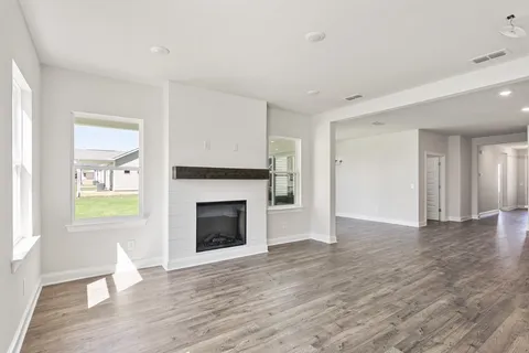 a view of an empty room with window and wooden floor