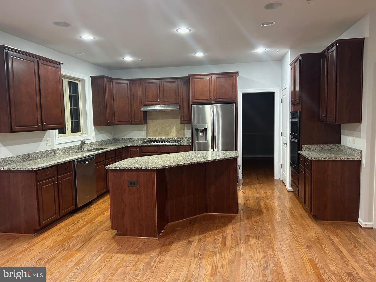 1101 Verbena Court Silver Spring, MD 20906 - Photo 6 of 36 a kitchen with kitchen island granite countertop wooden cabinets a refrigerator and a sink