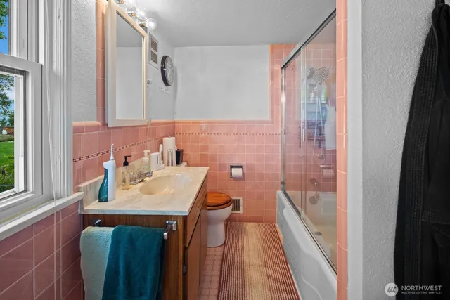 a bathroom with a sink a toilet a mirror and shower