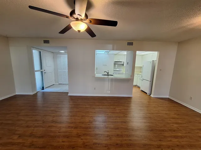 a view of an empty room with window and wooden floor