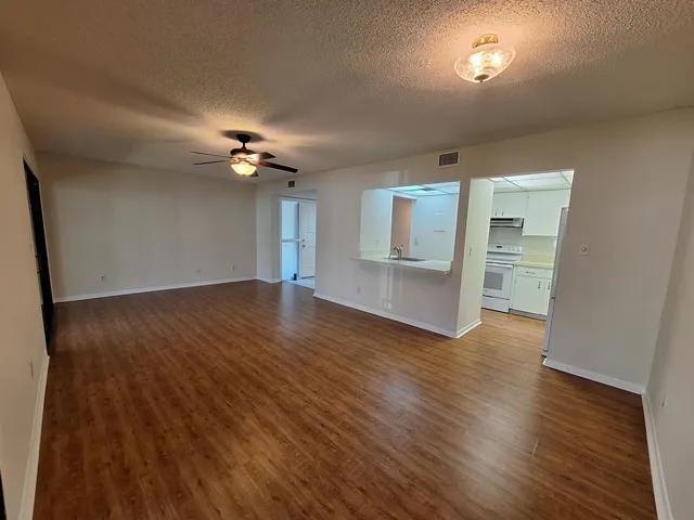 an empty room with wooden floor a ceiling fan and windows