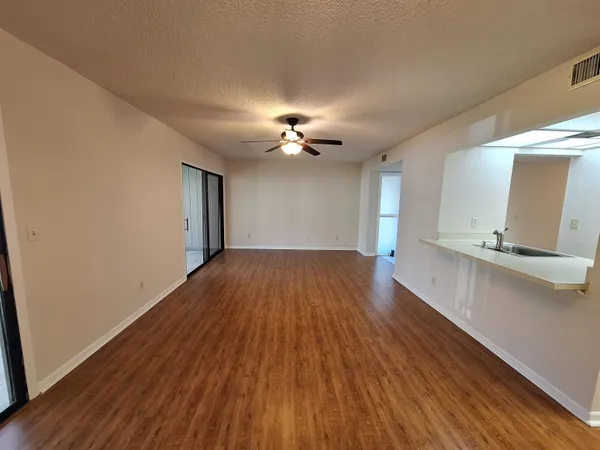 a view of a big room with wooden floor and a ceiling fan