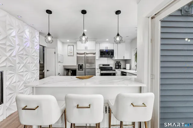 a kitchen with stainless steel appliances kitchen island granite countertop a table chairs and a refrigerator