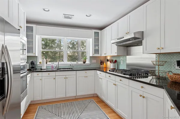 a kitchen with granite countertop a sink stainless steel appliances and cabinets