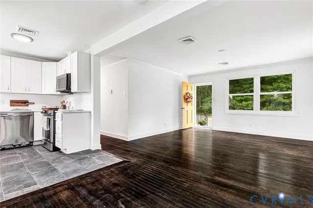 a view of an empty room with window and wooden floor