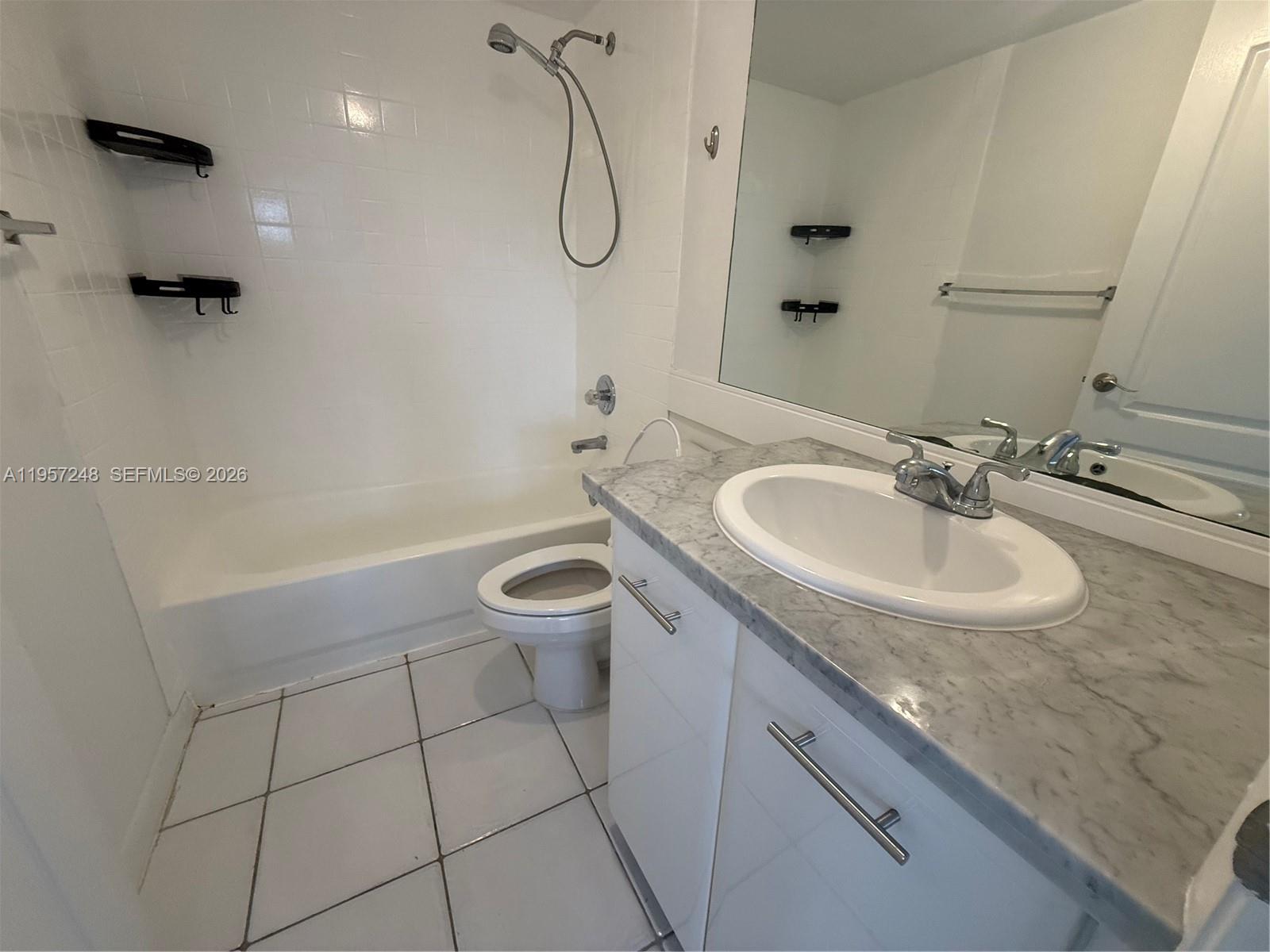 3052 Southwest 27th Avenue, Unit 301 Miami, FL 33133 - Photo 15 of 16 a bathroom with a granite countertop sink a toilet and a bathtub