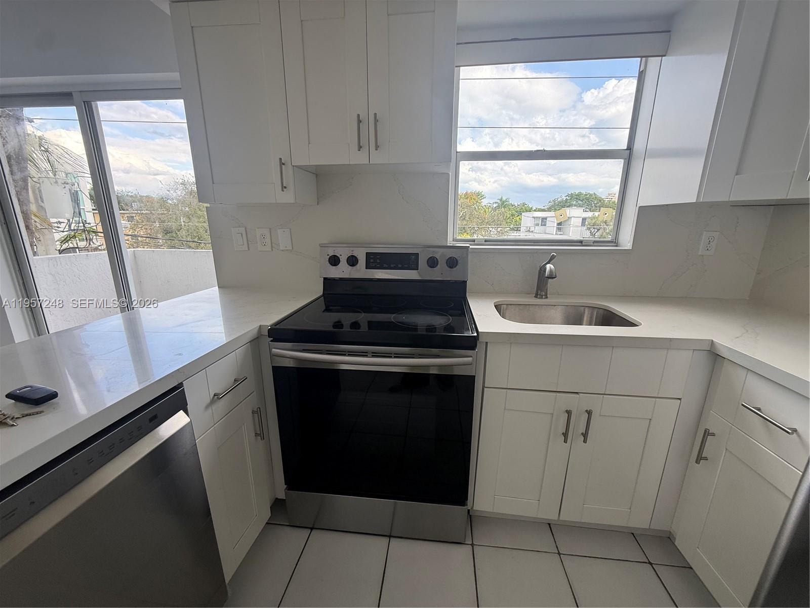 3052 Southwest 27th Avenue, Unit 301 Miami, FL 33133 - Photo 5 of 16 a kitchen with a sink stove top oven and cabinets