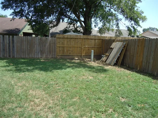 a view of a backyard with a trees and wooden fence
