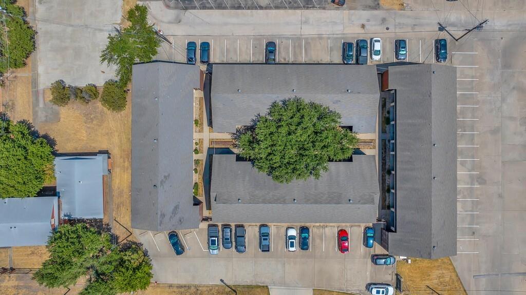 1362 South 12th Street, Unit 22 Waco, TX 76706 - Photo 27 of 31 Multiple buildings featuring sloped roofs, a central courtyard with mature trees, and paved parking areas