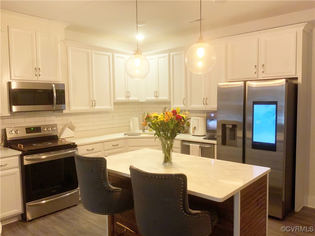 4324 Saunders Station Loop, Unit A Henrico, VA 23233 - Photo 12 of 30 a kitchen with stainless steel appliances a stove a sink a microwave a dining table and chairs