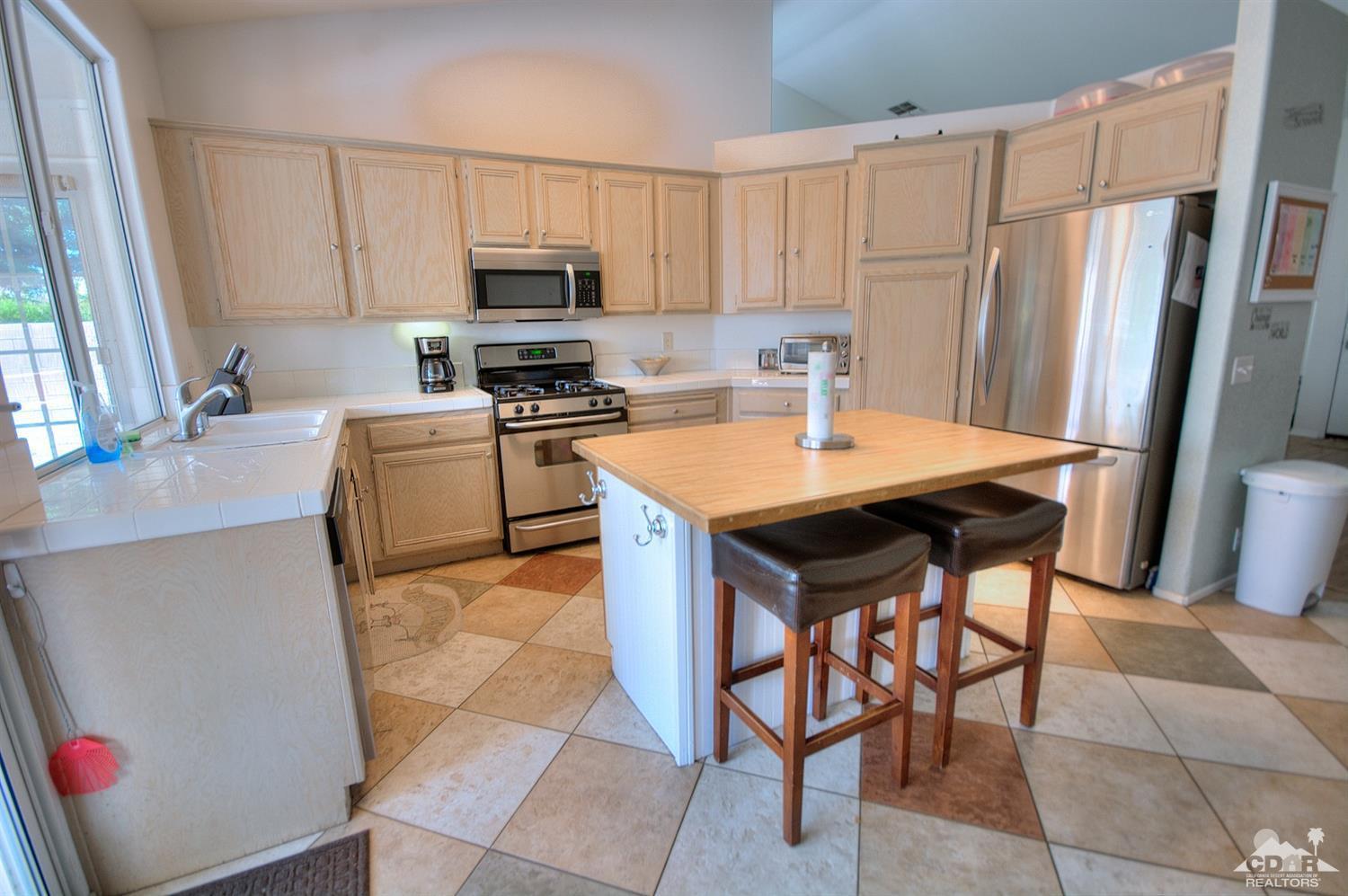 68237 Pasada Road Cathedral City, CA 92234 - Photo 11 of 30 a kitchen with a refrigerator a stove a microwave and a dining table