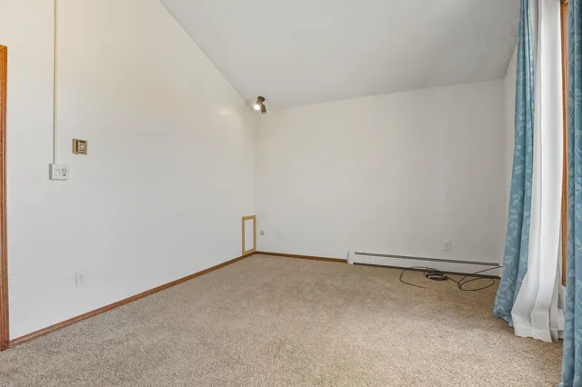an empty room with chandelier fan and windows