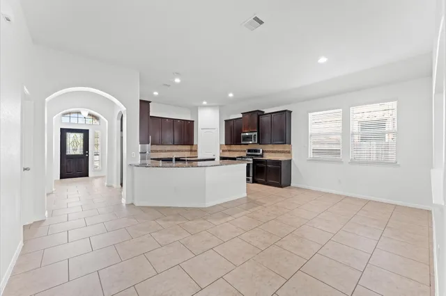 a large kitchen with kitchen island granite countertop a stove top oven a sink a counter space and cabinets