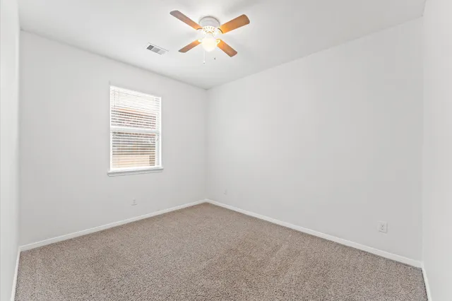 an empty room with a window and a fan