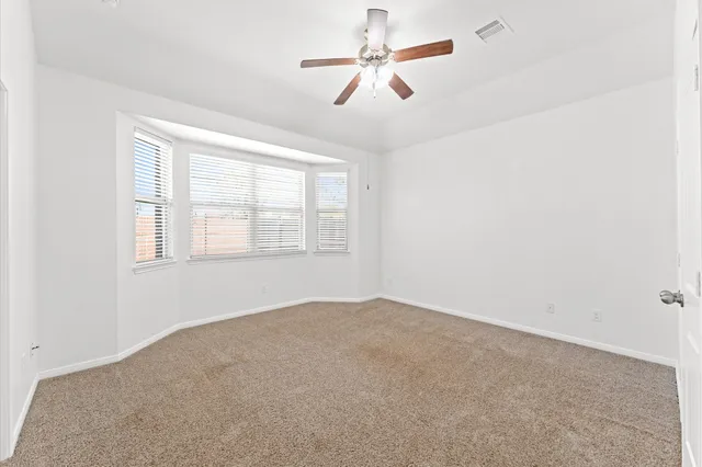 an empty room with windows and fan