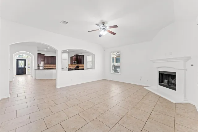 a view of a livingroom with a fireplace a ceiling fan and windows