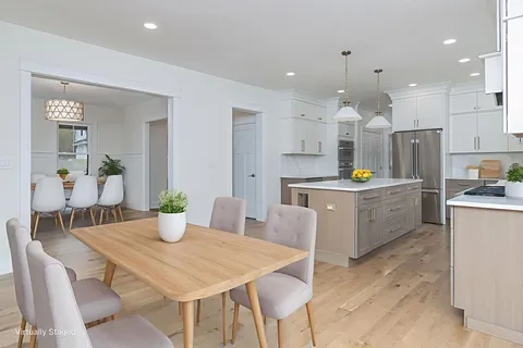a kitchen with stainless steel appliances kitchen island granite countertop a dining table chairs and white cabinets