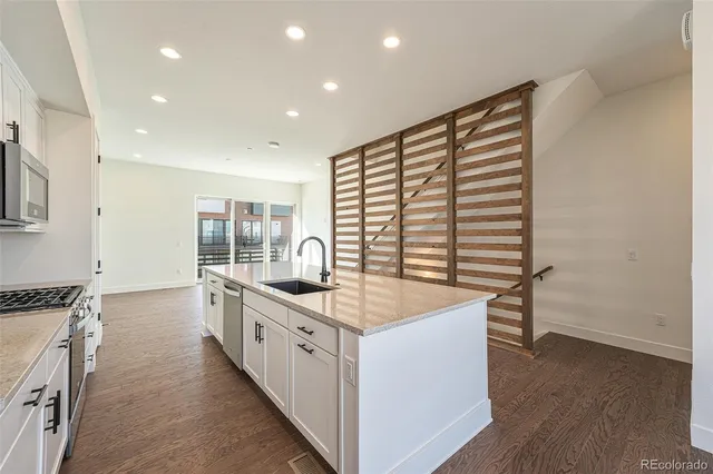 a kitchen with stainless steel appliances a white stove top oven a sink dishwasher and a refrigerator with wooden floor