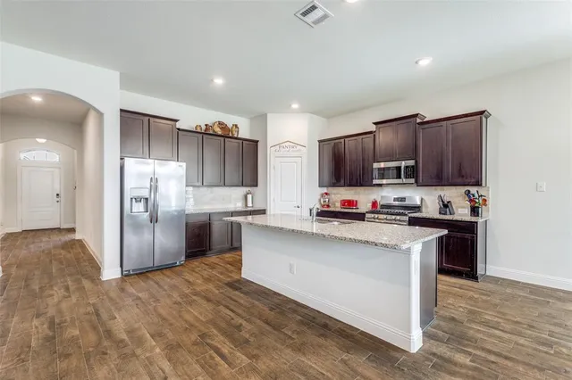 a kitchen with stainless steel appliances granite countertop a sink stove and refrigerator with wooden floor